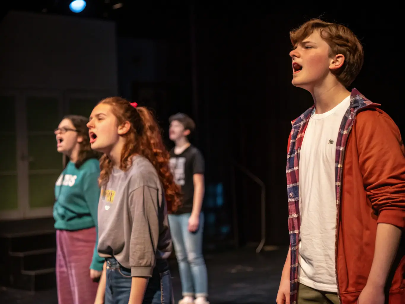 A heartwarming image of teenagers rehearsing for a theatre performance, highlighting the camaraderie and collaborative spirit fostered at ALQD.